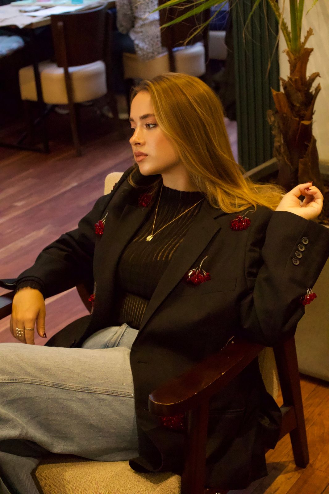 Model sitting back in a wooden armchair, looking to the side